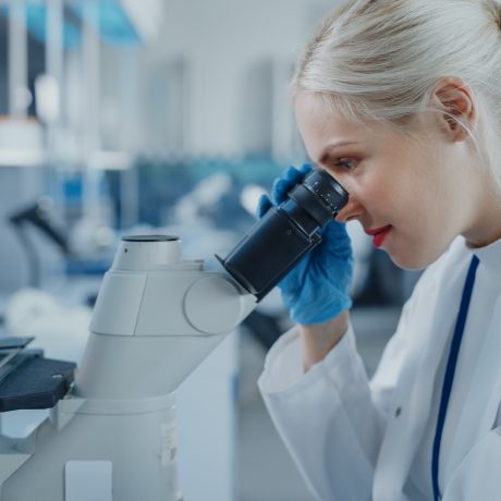 Modern Medical Research Laboratory: Portrait of Female Scientist Looking Under Microscope, Analysing Biochemicals Samples. Advanced Scientific Lab for Medicine, Microbiology Development